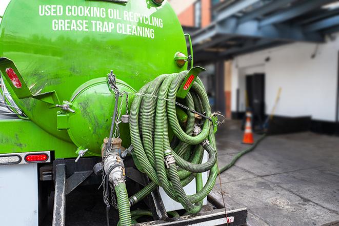 worker pumping grease trap at commercial kitchen in Pearce